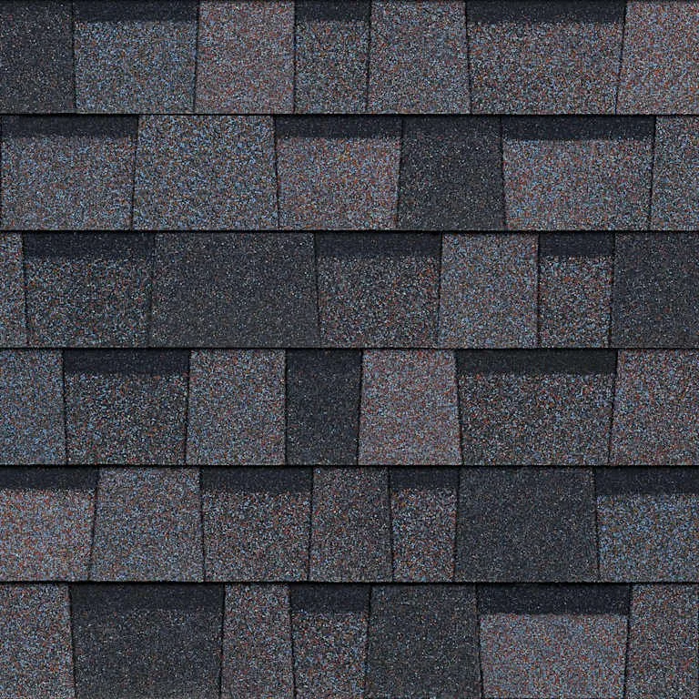 Close-up of a roof with multiple layers of asphalt shingles in a dark color with a speckled pattern.
